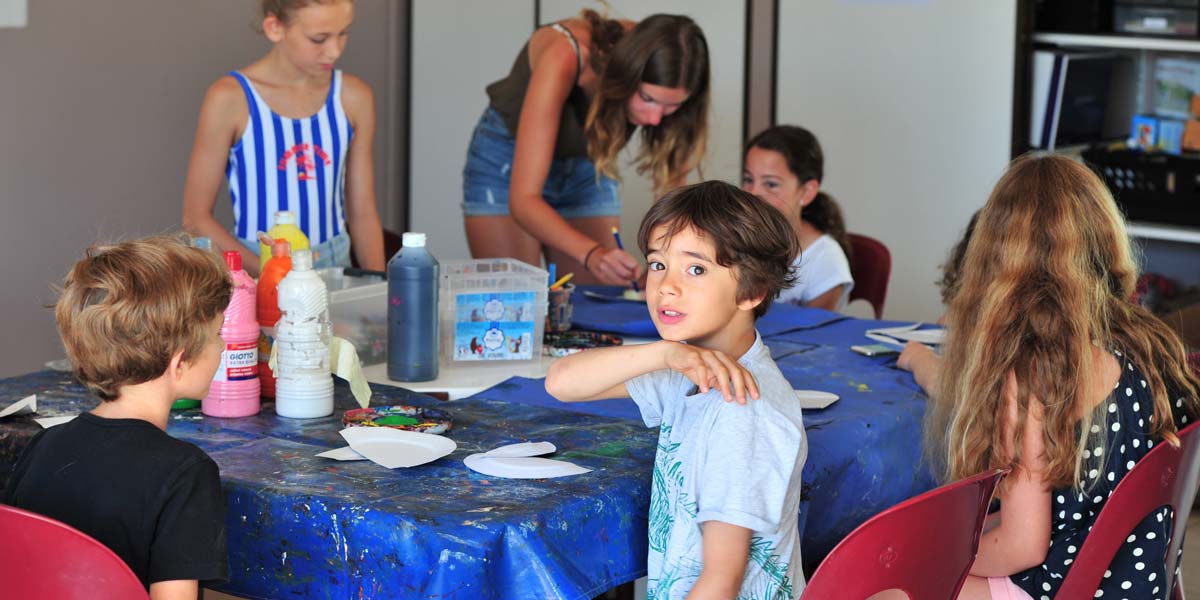 Kinder spielen um einen Tisch im Kinderclub des Campingplatzes in der Vendée