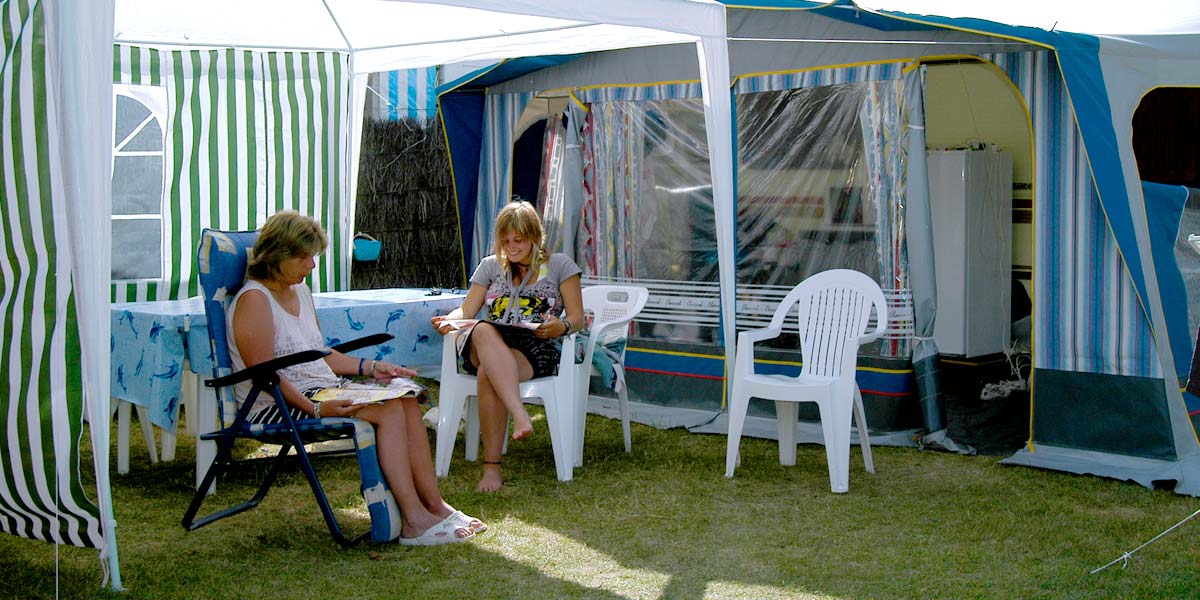 Lesendes Paar unter der Markise ihres Zeltes auf einem Campingplatz in der Vendée
