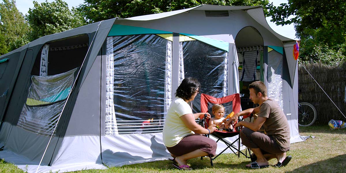 Parents with their baby in front of their tent at Les Écureuils campsite in Vendée