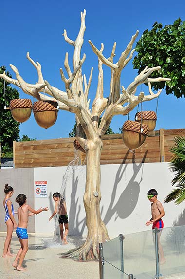 Enfants jouant sous les jets d'eau en forme d'arbre au camping Les Écureuils en Vendée