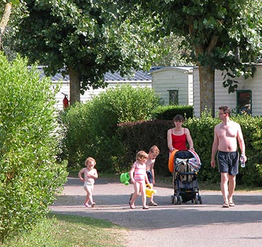 Familie van kampeerders op een steegje in het park van camping Les Écureuils in Saint-Hilaire-de-Riez