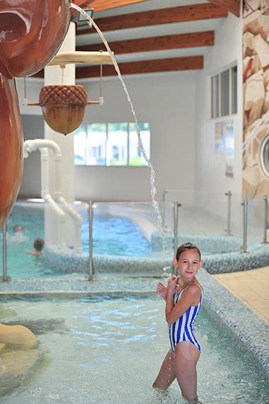 Klein meisje onder een waterstraal in het overdekte zwembad van de camping bij Saint-Gilles-Croix-de-Vie