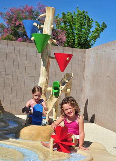 Spelende kinderen onder een waterstraal en waterspelletjes in het peuterbad van de camping in Vendée