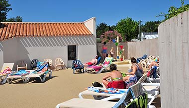 Strand en ligstoelen bij het zwembad op camping Les Écureuils in Vendée