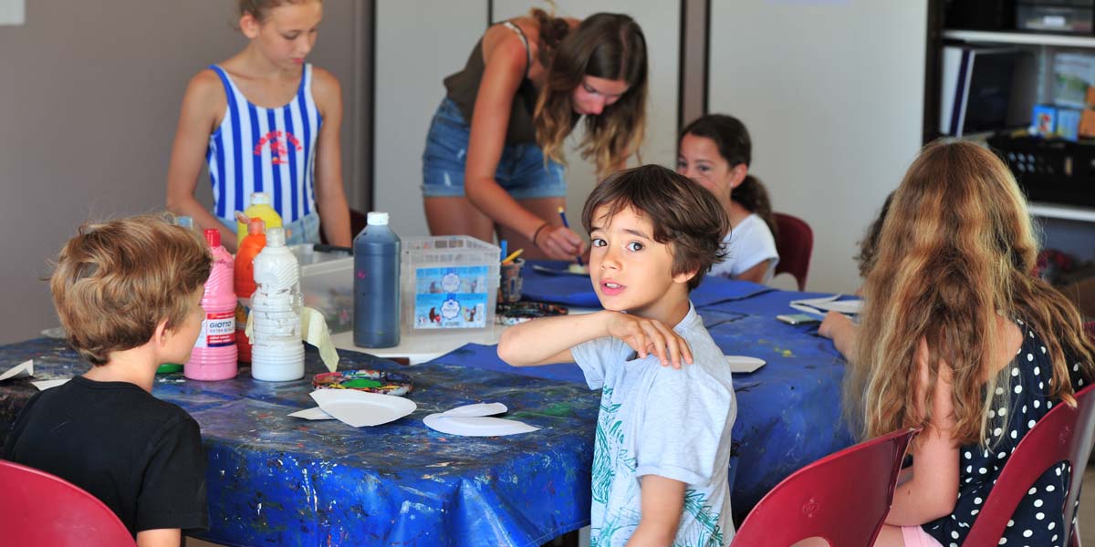 Spelende kinderen rond een tafel in de kinderclub van de camping in Vendée