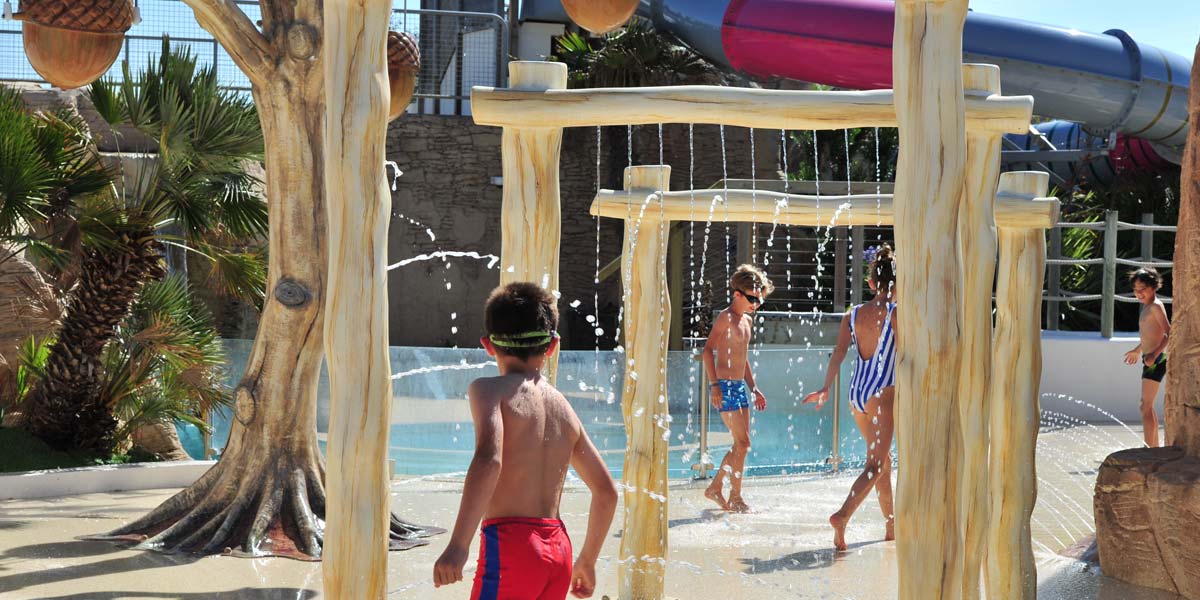 Enfants sous des jets d'eau dans l'espace aquatique du camping en Vendée