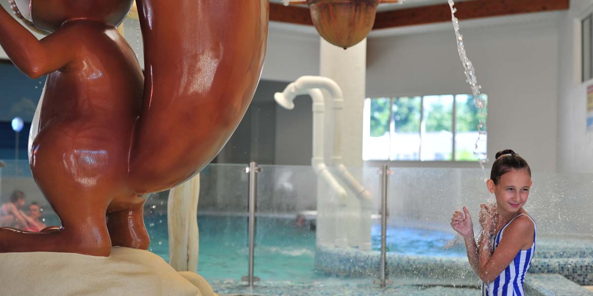 Junges Mädchen unter einem Wasserstrahl im Wasserbereich von Saint-Hilaire-de-Riez in der Vendée