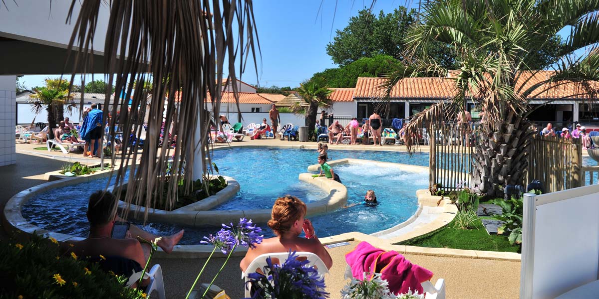 Beach with palm trees around the aquatic area of the campsite in Vendée